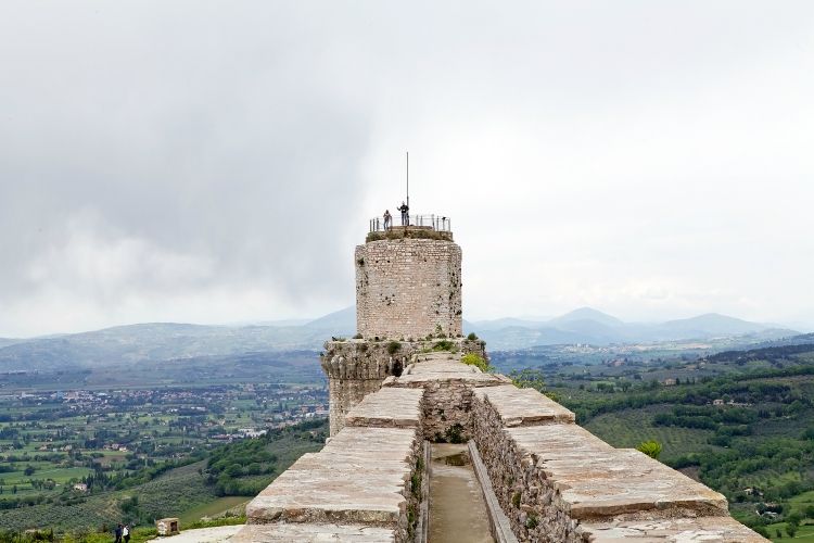 Tourists are visiting the Rocca Maggiore, Assisi, Italy, with panorama. Rocca Maggiore dominated by more than eight hundred years the citadel of Assisi and the valley of Tescio. The first documented regarding the fortress date back to 1173.