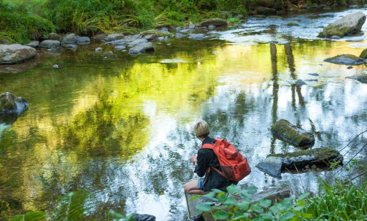 Young photographer taking photos with smartphone along the river Barle, Somerset, UK