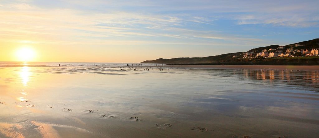 empty beach with a few surfers and dog walkers in the evening, uk