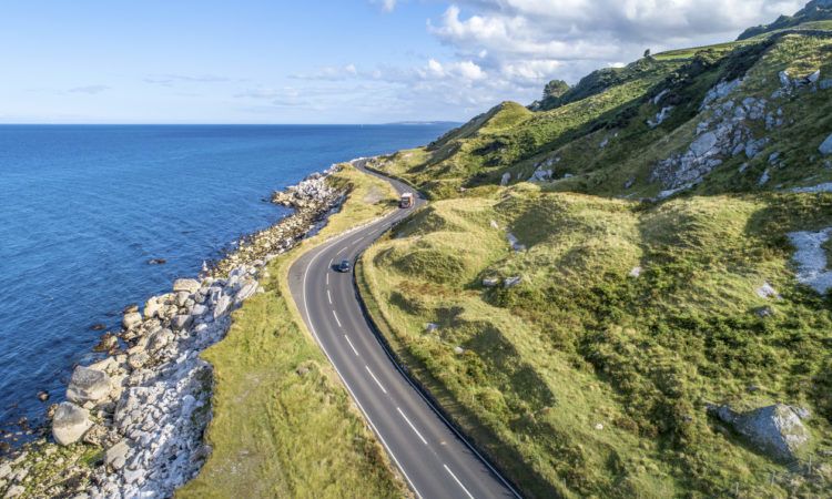 Causeway Costal Route with cars, a.k.a. Antrim Coastal Road on eastern coast of Northern Ireland, UK.
