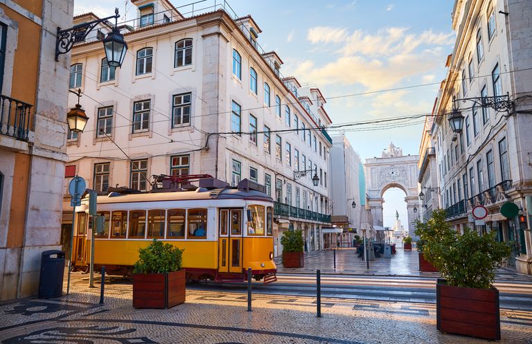 Lisbon, Portugal. Yellow touristic retro tram. Triumphal Arch of Rua Augusta near Praca do Comercio (Commercial Square. Sunny day in famous tourist place Lisboa.