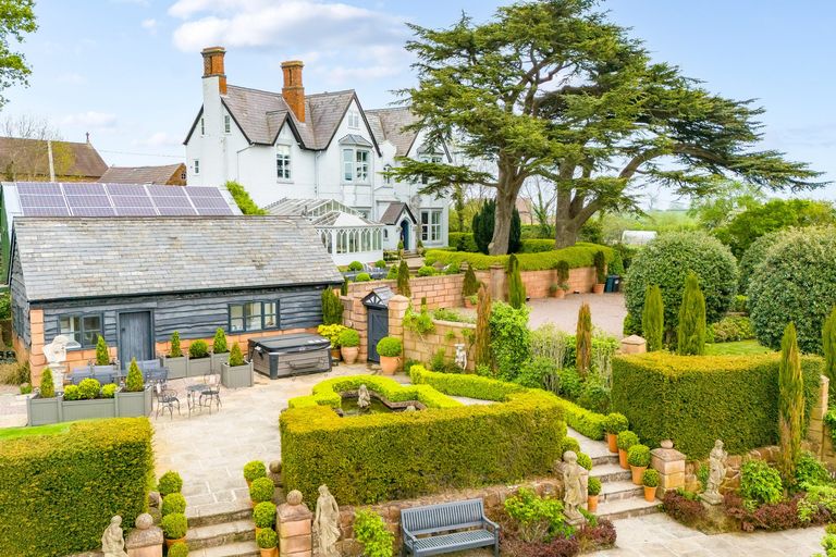 view of house with neat garden and hot tub