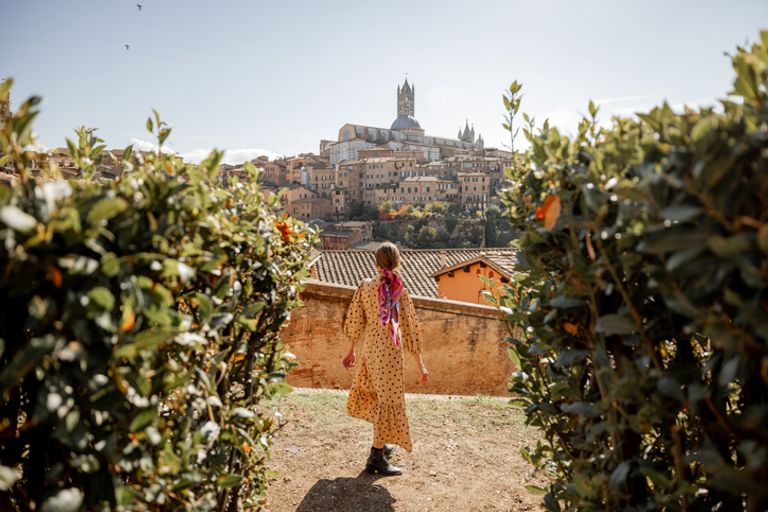 Woman walks on background of cityscape of Siena old town