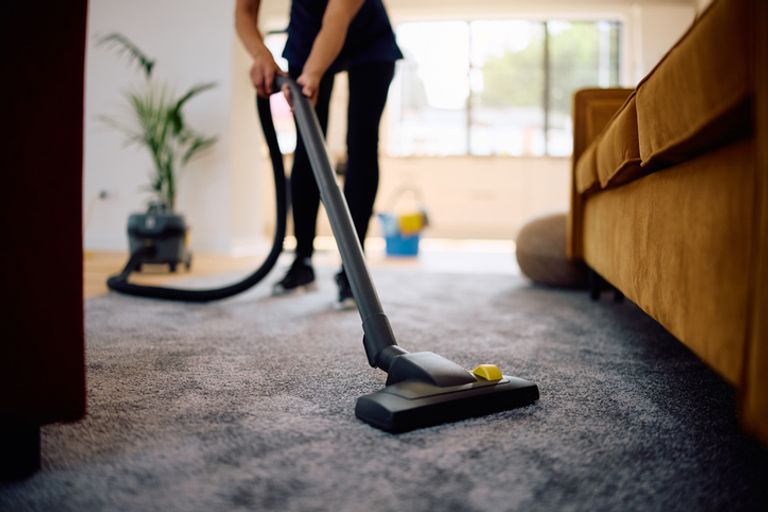 Close up of woman vacuuming while working professional cleaner.