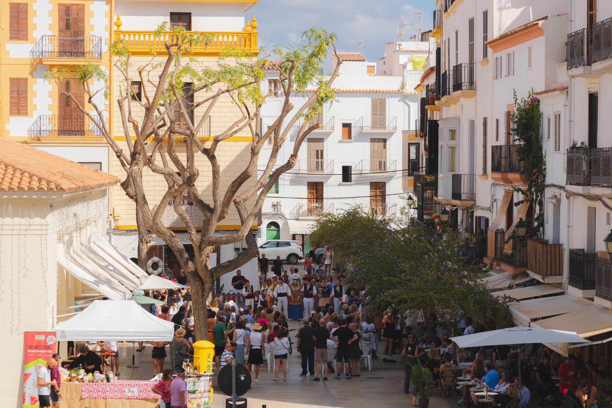 Ibiza, Spain - October 8, 2023: Lively street scene in Ibiza Town, capturing a vibrant local festival with people gathering under the Mediterranean sun.