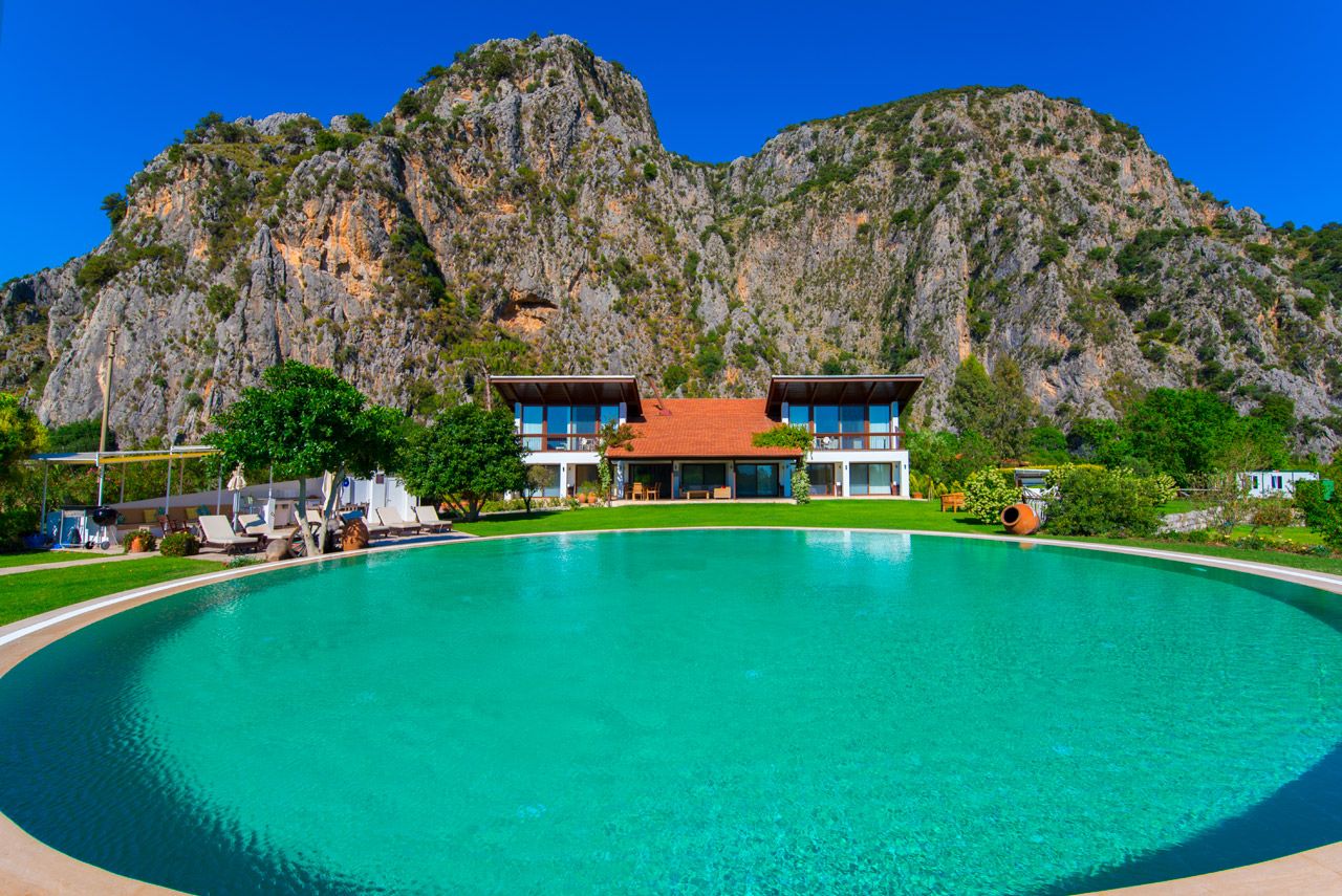 Large swimming pool view with villa and mountains in the background